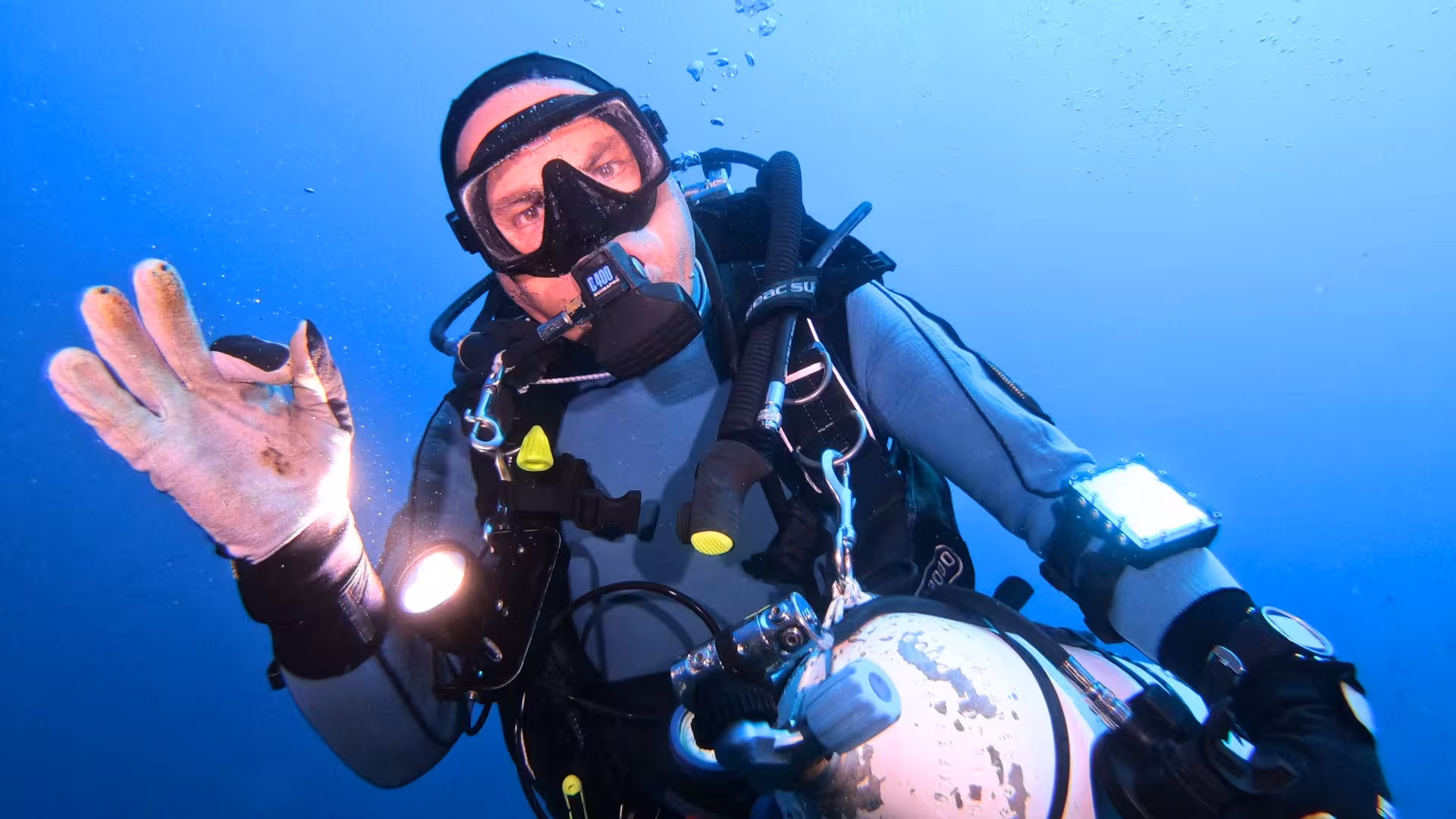 Scuba diver giving an OK sign in the Gulf of Angels, Cagliari, highlighting the area's diving adventures.