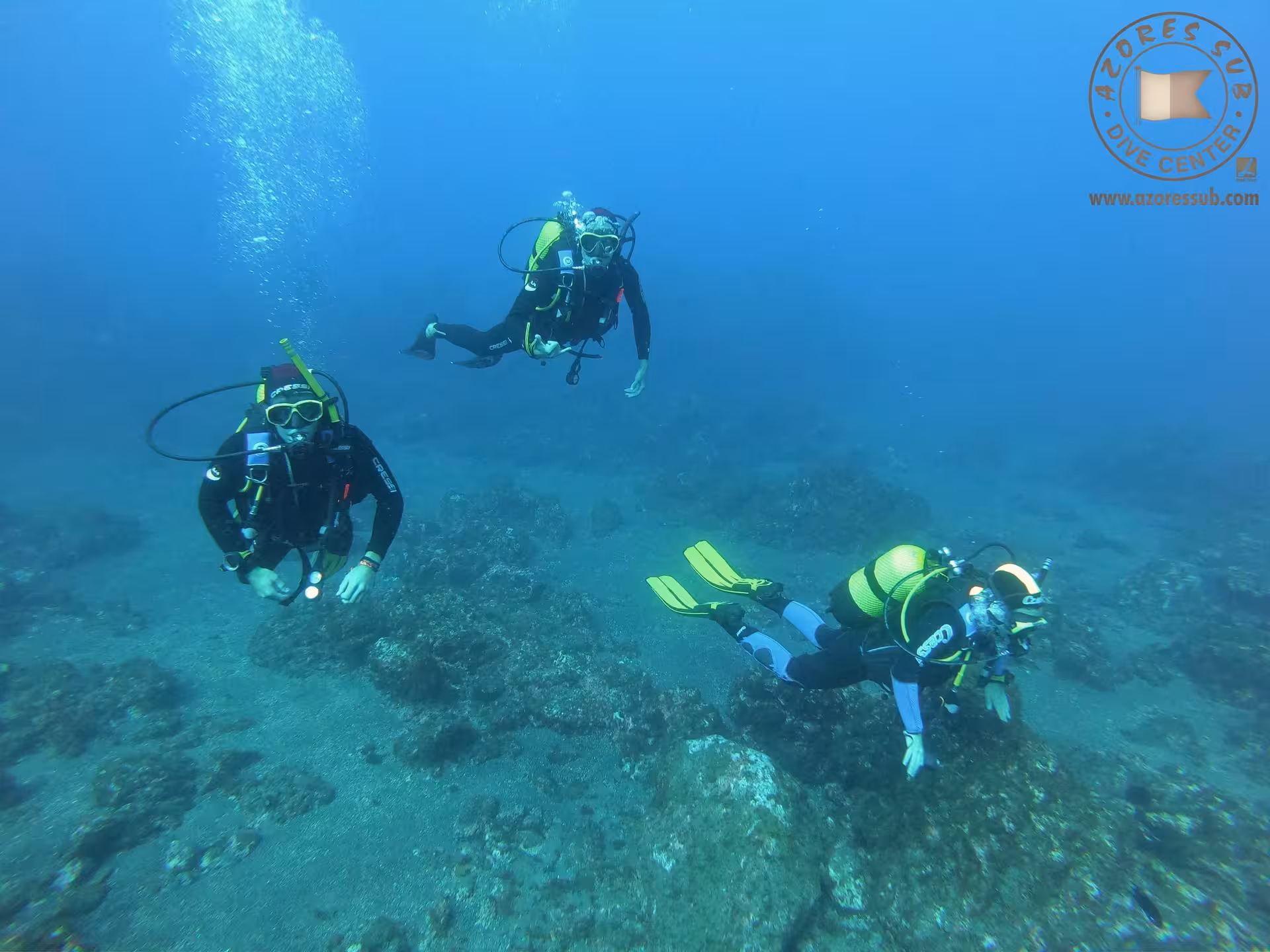 Scuba divers exploring rocky seabed on ocean dive for Baptism in Pool and Sea beginner experience