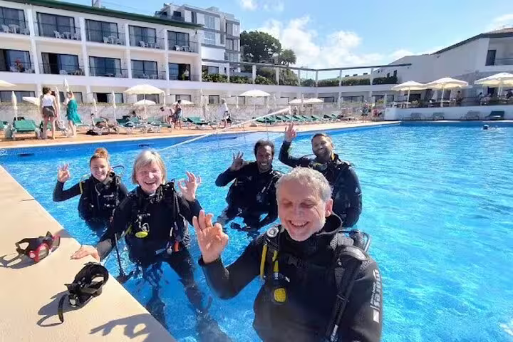 Group of scuba divers in wetsuits enjoying a sunny pool session in Funchal, Madeira, preparing for an unforgettable underwater adventure.