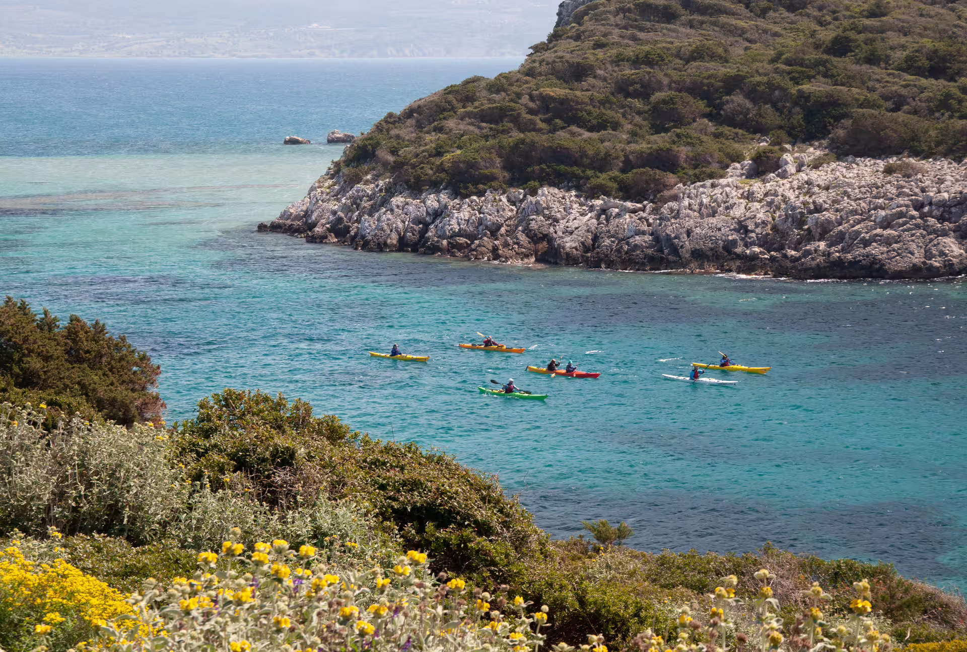 Guided sea kayak tour in Navarino Bay, paddling turquoise water along rocky coastline near Pylos, Greece