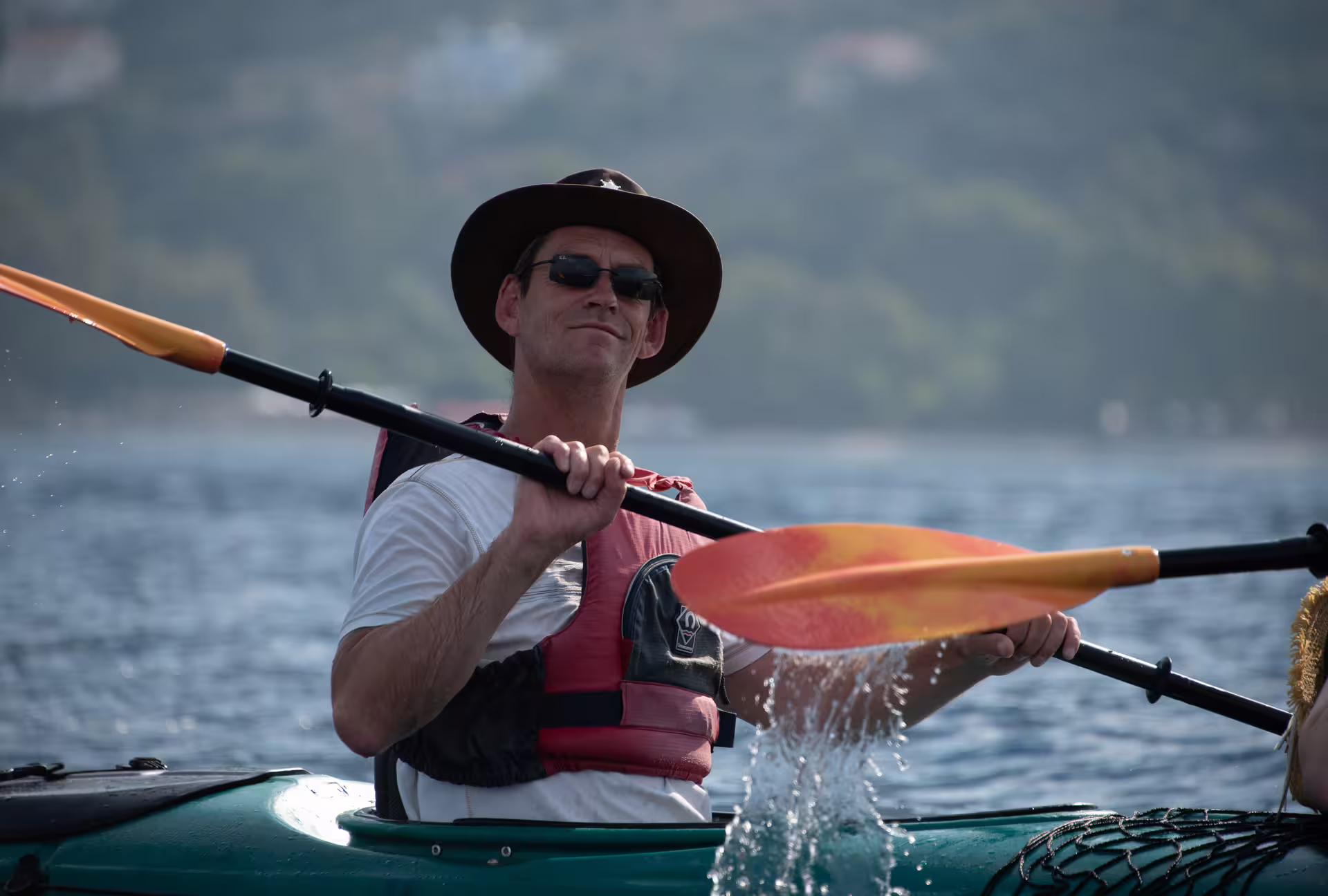 Sea kayak tour in Kalamata with paddler in life jacket and hat, cruising calm waters of the Messinian Gulf