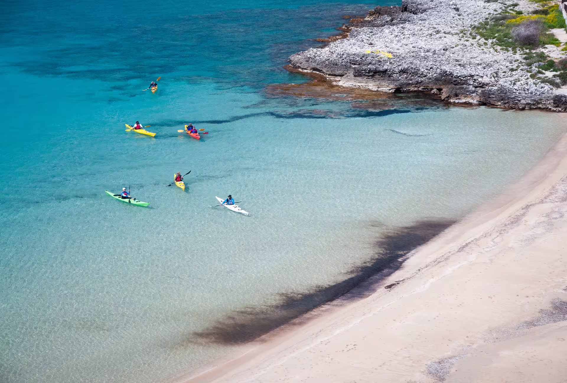 Guided sea kayak tour in Kardamyli and Stoupa, paddlers gliding in crystal-clear water by sandy beach