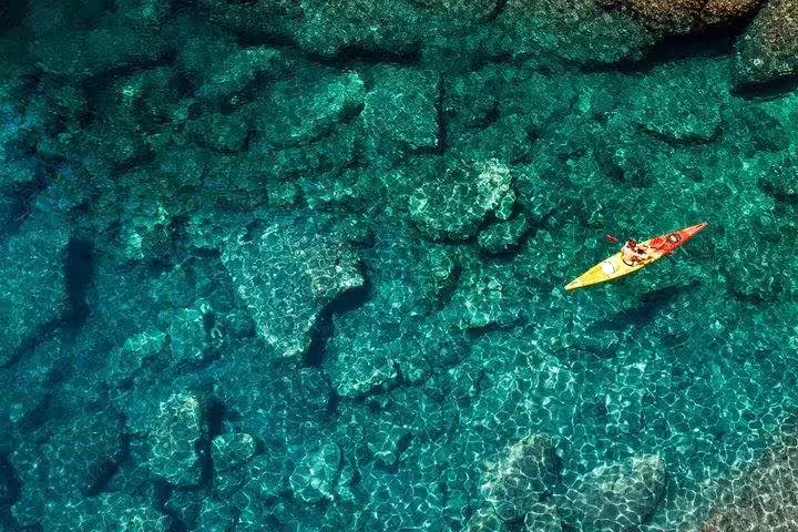 Aerial view of sea kayak over crystal-clear turquoise water and reefs, perfect for snorkeling adventure tour