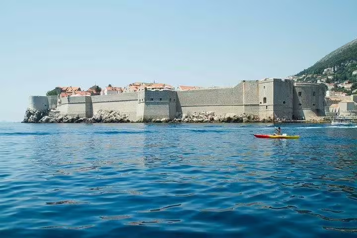 Sea kayaker paddling past a historic coastal fortress on a guided sea kayaking and snorkeling adventure