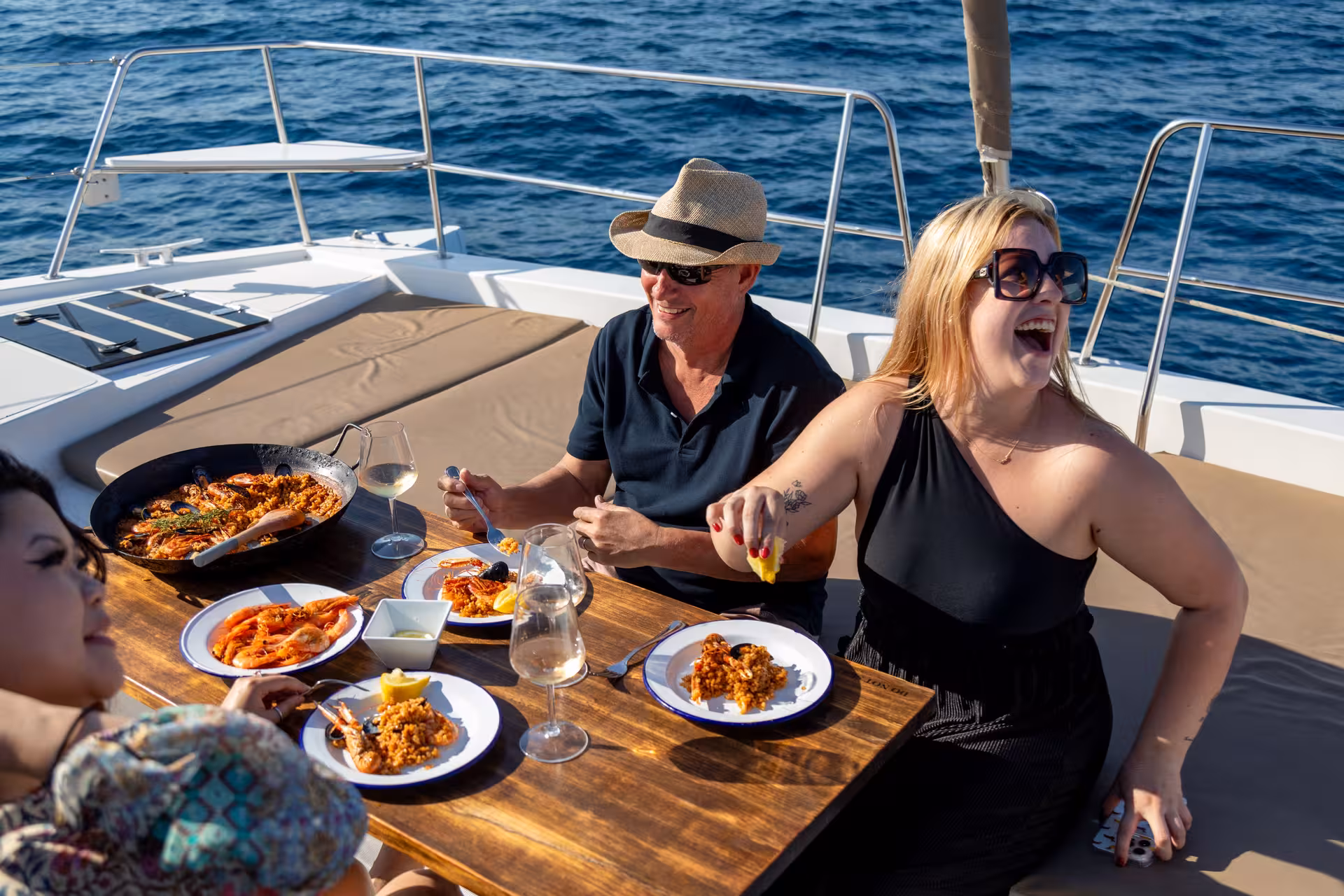 Guests enjoy seafood paella and wine on a catamaran, Barcelona sailing paella masterclass with ocean views