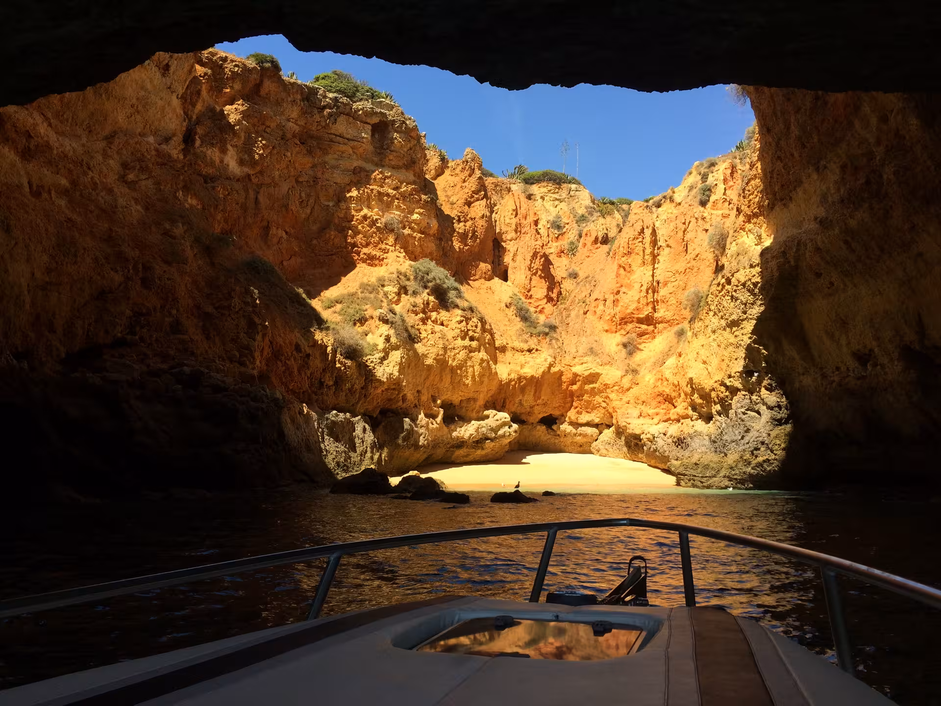 View from a Seasiren cave tour boat entering a hidden Algarve grotto with golden cliffs and a secluded sunlit beach inside