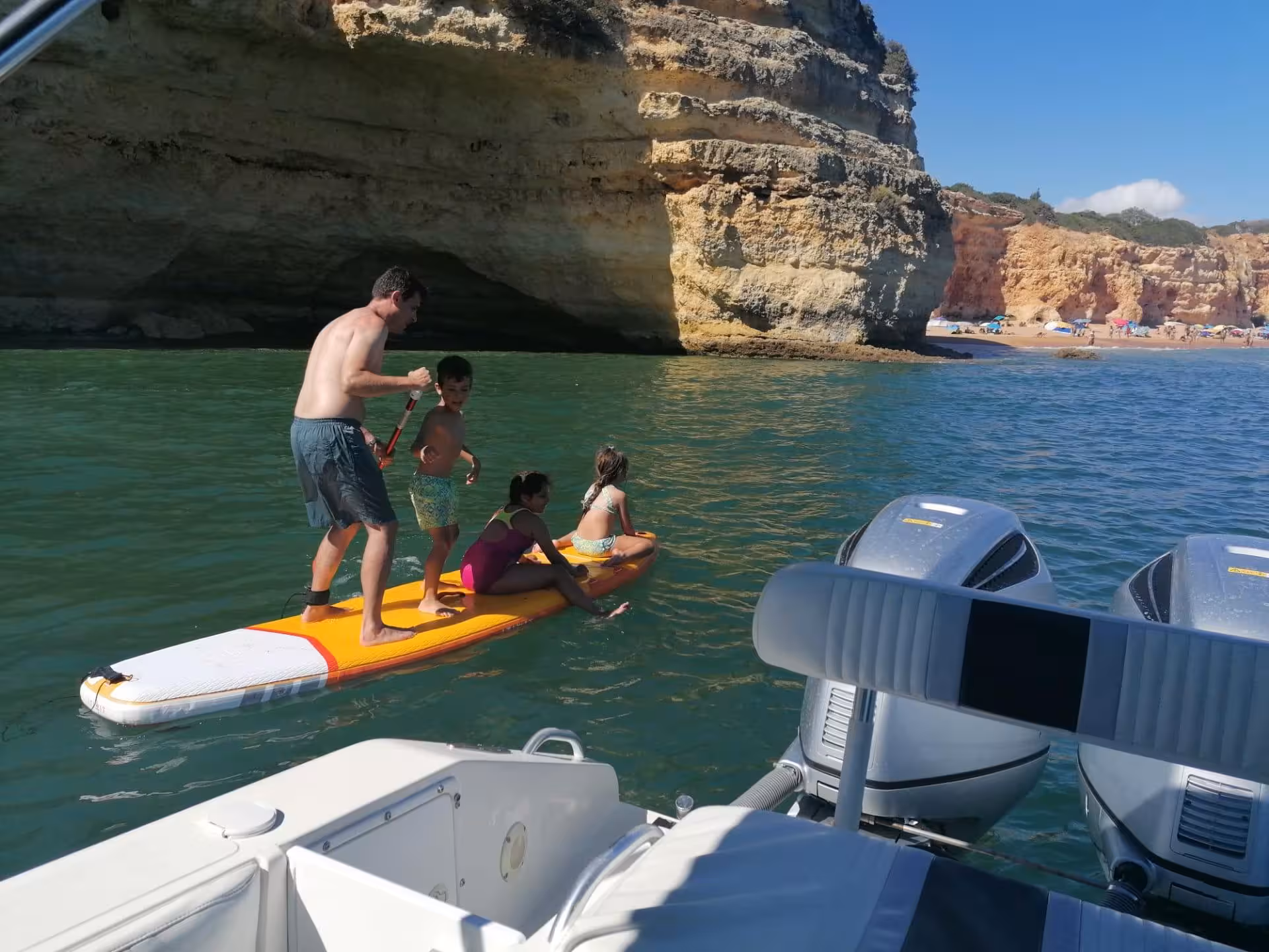 Family enjoying paddleboarding beside the Seasiren Private Tour 3H boat near Algarve’s dramatic cliffs and sandy beach