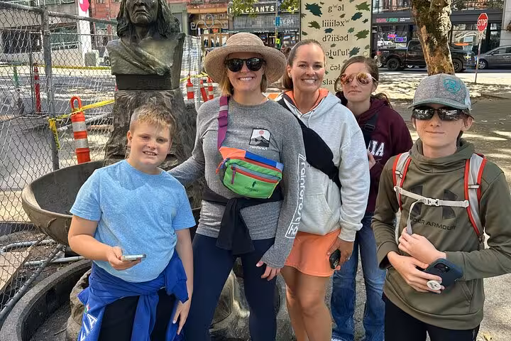 Group of five tourists posing near a bronze bust sculpture during a Seattle walking tour