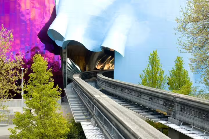 Seattle monorail track curving past colorful EMP Museum building with blue and purple panels