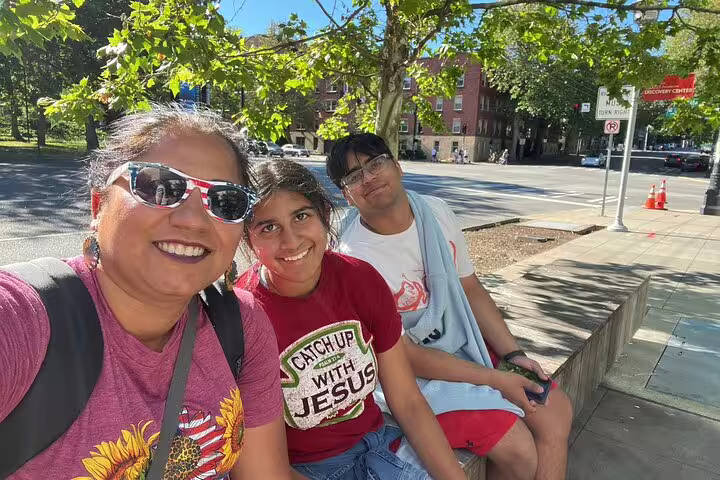 Three smiling tourists taking a selfie on a sunny Seattle street during a walking tour