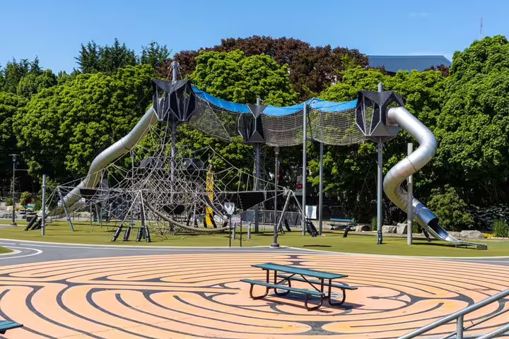 Modern rope climbing playground with tube slides and net structures in a Seattle park on a sunny day