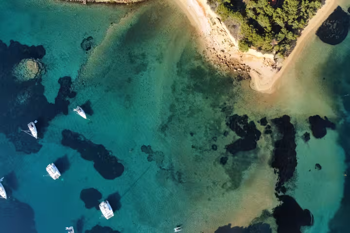 Drone view of secluded sandy bay with anchored boats and shallow turquoise water, Dolce far niente boat tour