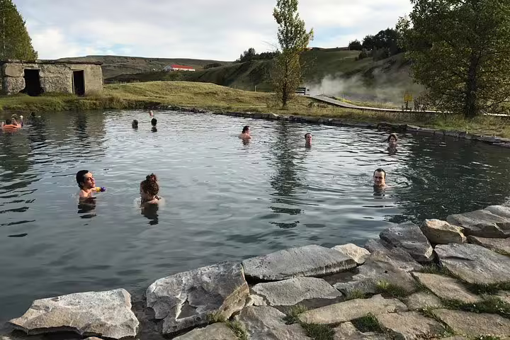 Visitors soaking in the Secret Lagoon geothermal hot spring pool in Iceland's countryside