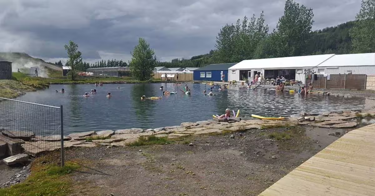 Swimmers enjoying the Secret Lagoon geothermal hot spring pool in Iceland on a cloudy day
