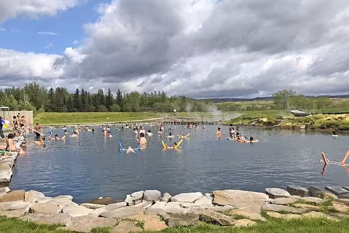Visitors enjoying a relaxing soak at Secret Lagoon natural hot spring on Iceland's Golden Circle tour