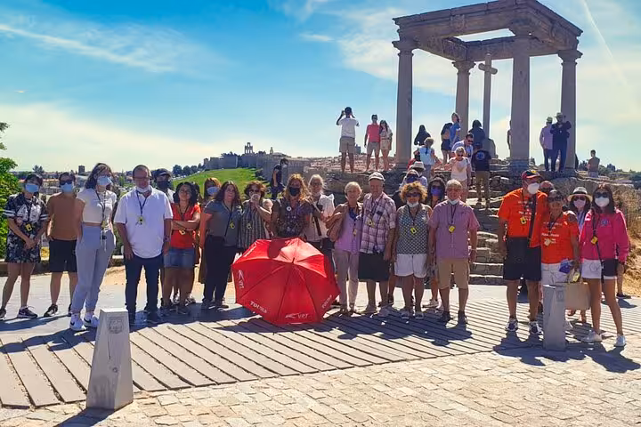 Tour group poses by ancient ruins in Avila during a Segovia and Avila day trip from Madrid with optional lunch.