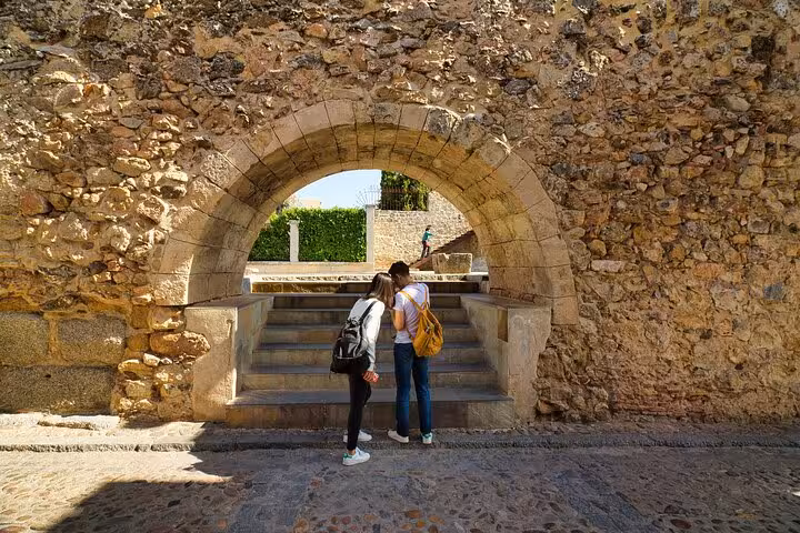 Two tourists explore an ancient stone archway in Segovia on a guided day trip from Madrid.