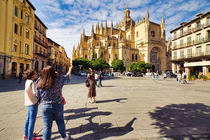 Tourists admire the stunning Gothic architecture of Segovia Cathedral on a sunny day trip from Madrid.