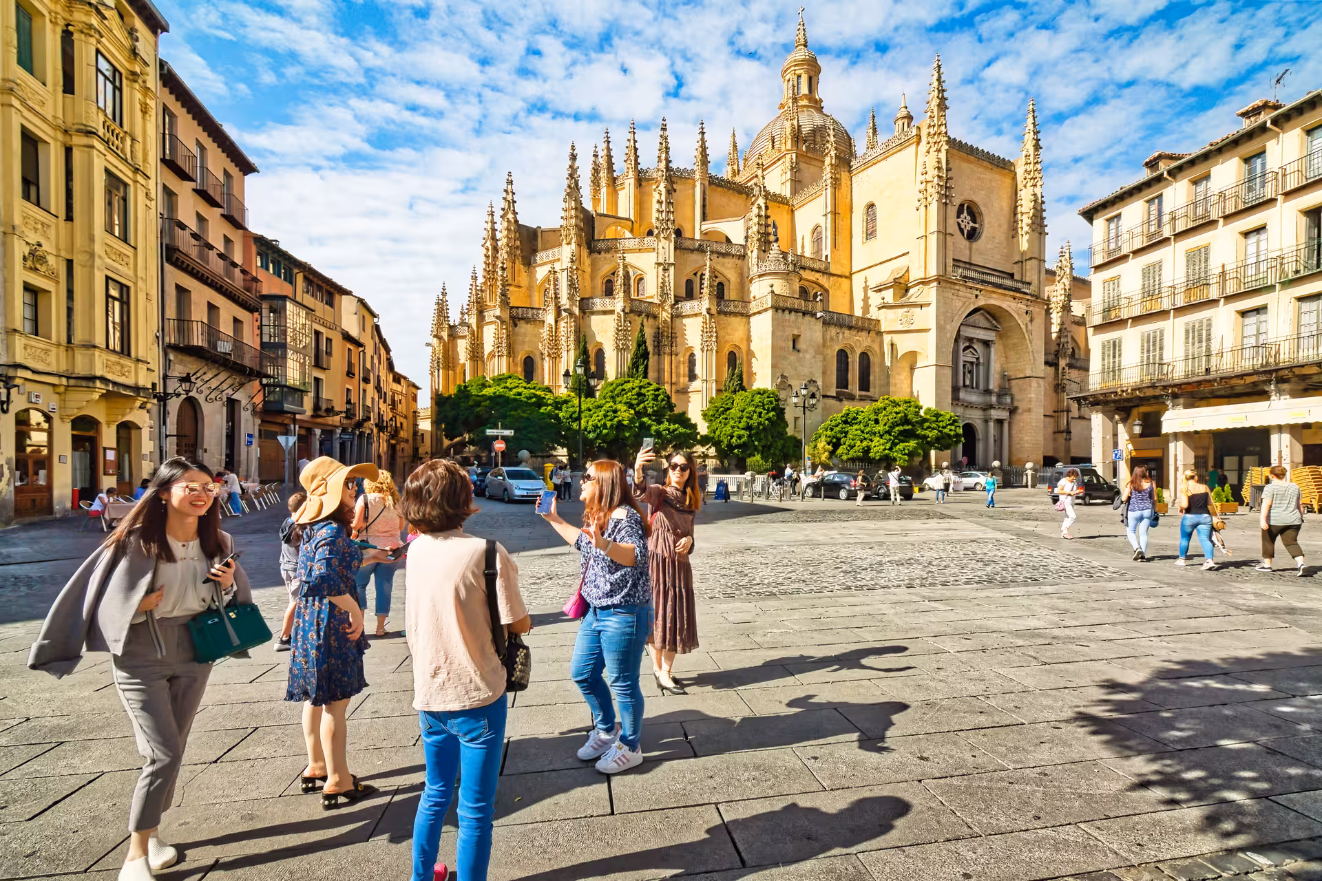 Visitors enjoying the lively atmosphere in front of Segovia Cathedral, a highlight of a full day tour from Madrid.