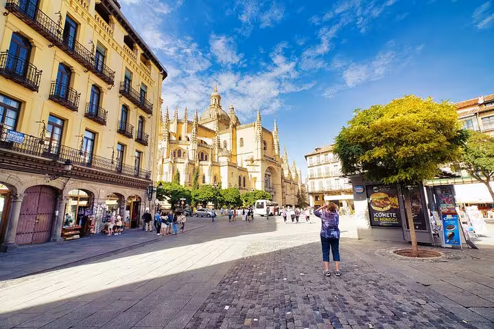 Visitors explore the bustling plaza with Segovia Cathedral in the backdrop, highlighting the Segovia and Avila guided tour.
