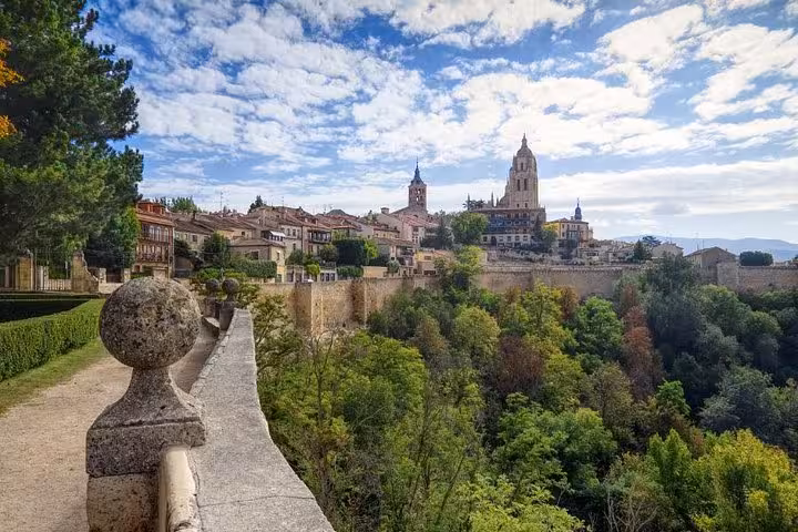 Scenic view of Segovia's historic skyline with Cathedral and lush landscape on a guided day trip from Madrid.