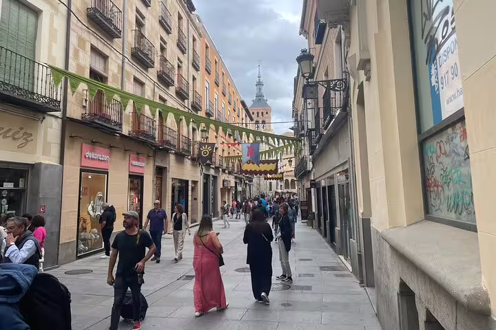 Segovia old town shopping street with festive banners, part of a private minivan tour from El Escorial Monastery