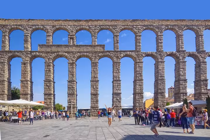 Tourists gather at the majestic Segovia Roman aqueduct, part of the Segovia and Avila day tour.