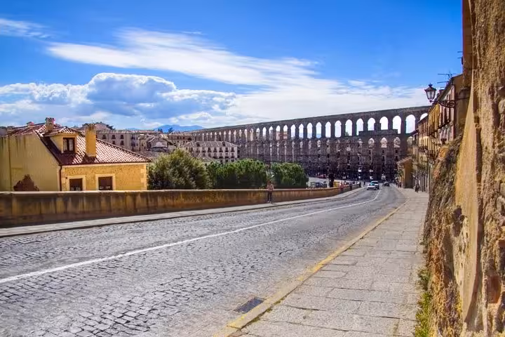 View of the ancient Roman aqueduct in Segovia, showcasing its impressive arches on a sunny day during a half-day trip from Madrid.
