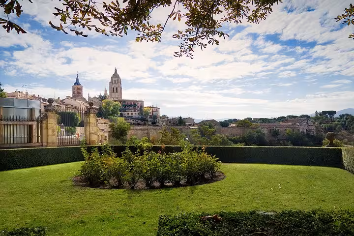 Scenic view of Segovia's historic skyline framed by lush gardens on a Segovia and Avila day trip from Madrid.