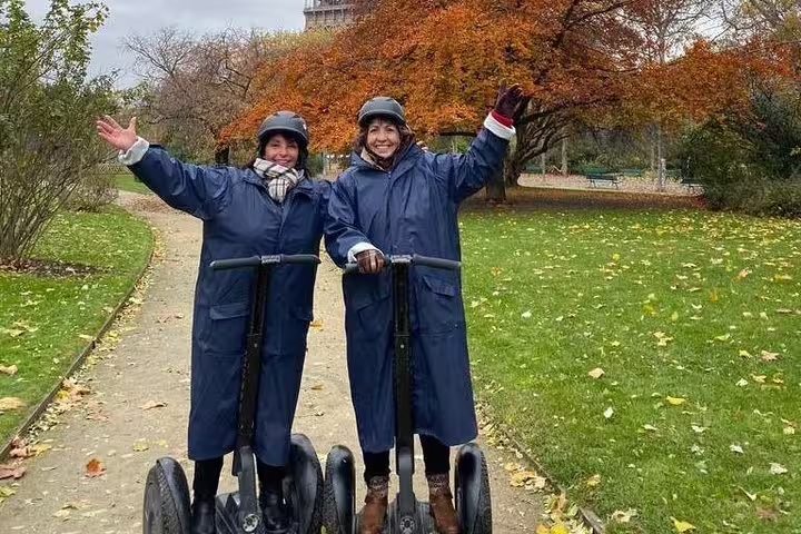 Two riders in helmets on Segways in a Paris park in autumn, enjoying a 3-hour private tour with a local guide