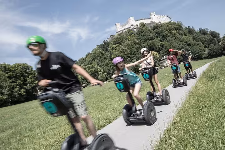 Group enjoying a Segway tour with views of Hohensalzburg Fortress in Salzburg, perfect for city and mountain exploration.