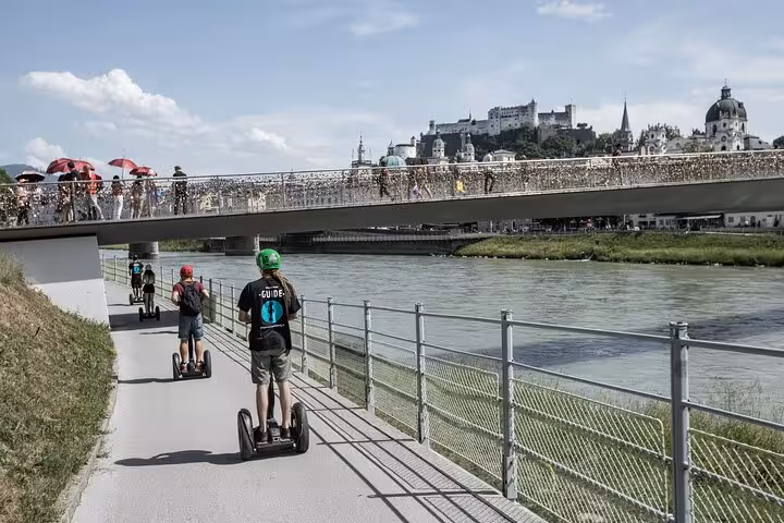 Tourists enjoying a scenic Segway ride along the Salzach River with views of Salzburg's historic skyline.