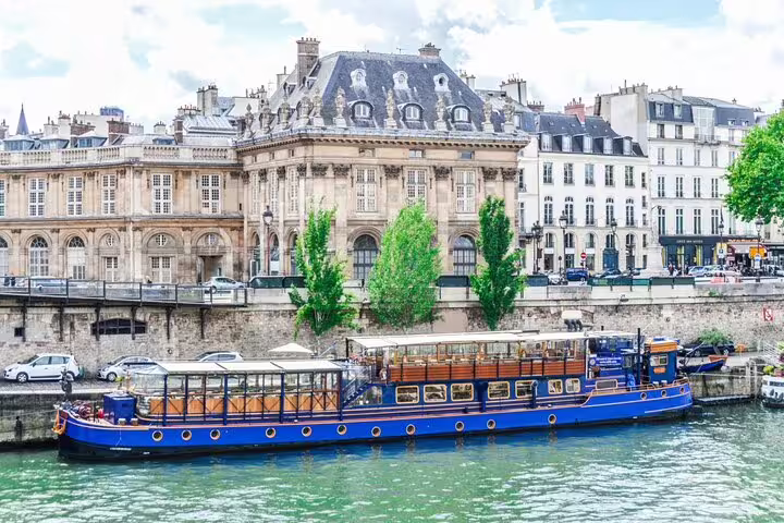 Blue river cruise boat on the Seine River with classic Haussmann buildings in Paris background
