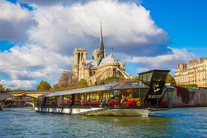 Seine River lunch cruise boat passing Notre-Dame Cathedral in Paris on a sunny day