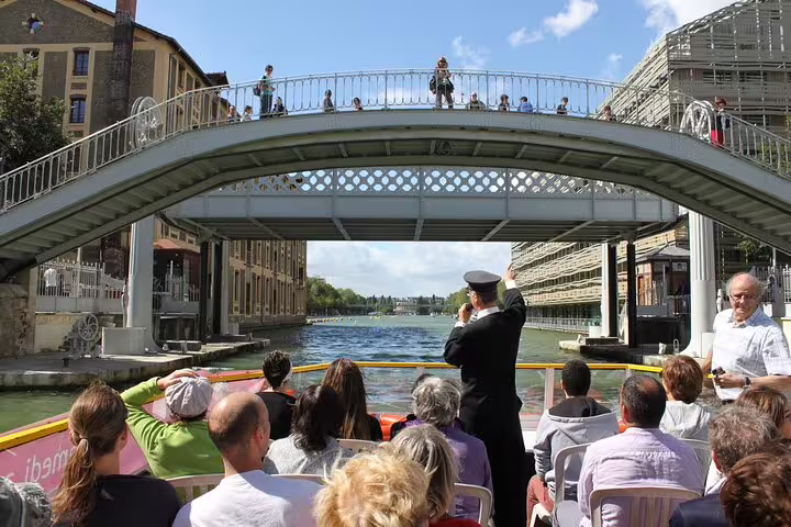 Tourists on a Seine River cruise boat passing under a decorative bridge in Paris
