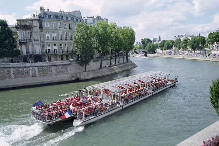 Bâteau Mouche dinner cruise boat filled with passengers sailing along the Seine River in Paris