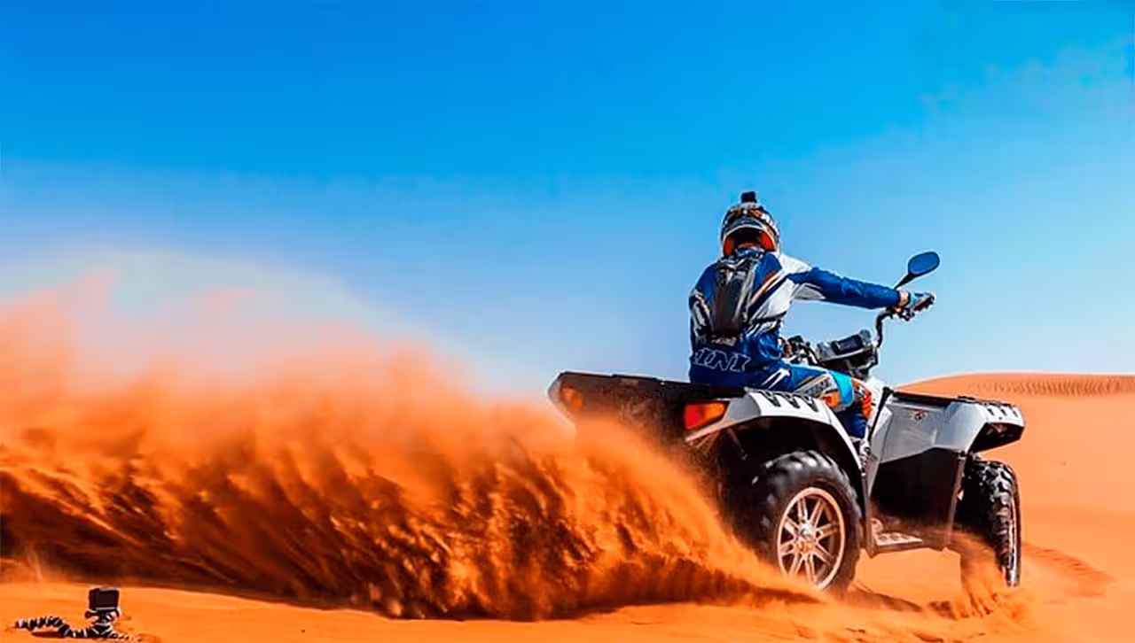 Adventurer on a thrilling self-drive buggy tour kicks up sand against a vivid blue sky in a scenic desert landscape.