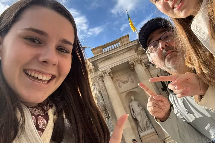 Tourists taking selfie in front of historic Bordeaux landmark building with Ukrainian flag