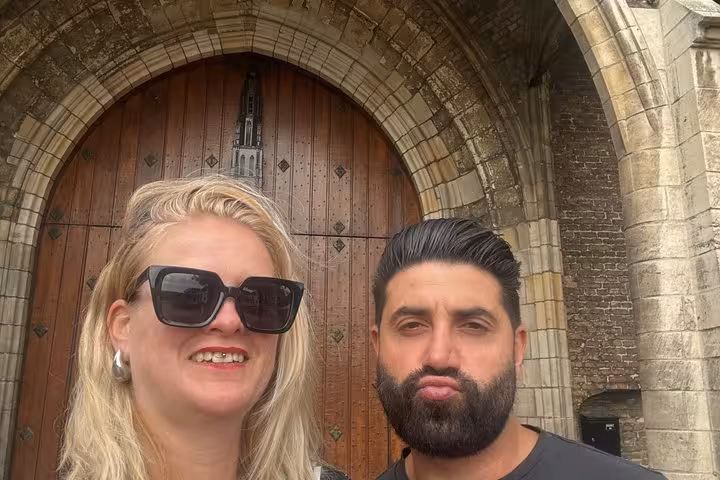Couple posing in front of historic stone church arched doorway in Delft during walking tour