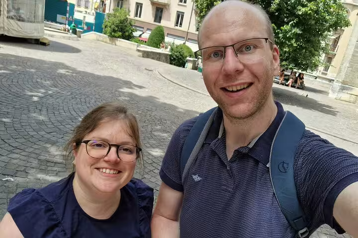 Couple smiling during a self-guided walking tour in Geneva's historic cobblestone square