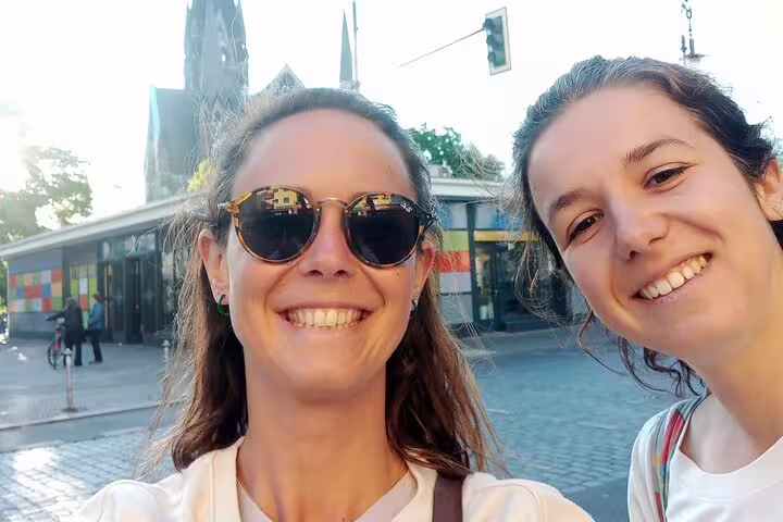 Two smiling women taking a selfie on a street in Kreuzberg Berlin with a church spire in background