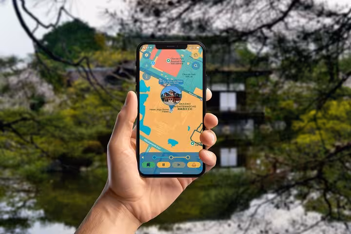 Hand holding smartphone displaying self-guided walking tour map of Kyoto's historic east side with Japanese temple background