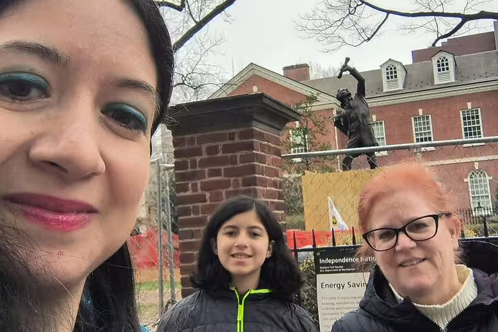 Three visitors taking a selfie at Independence National Historical Park with bronze statue and historic building behind