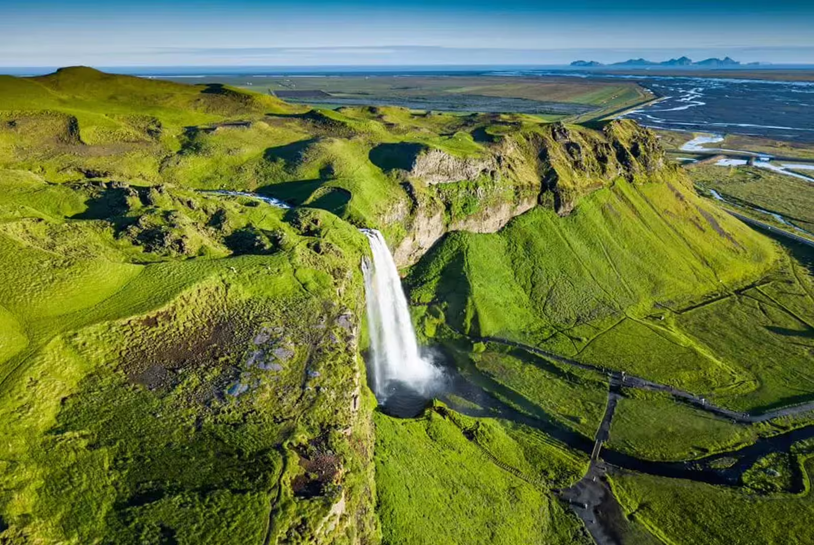 Aerial view of Seljalandsfoss waterfall cascading down green cliffs on Iceland's south coast