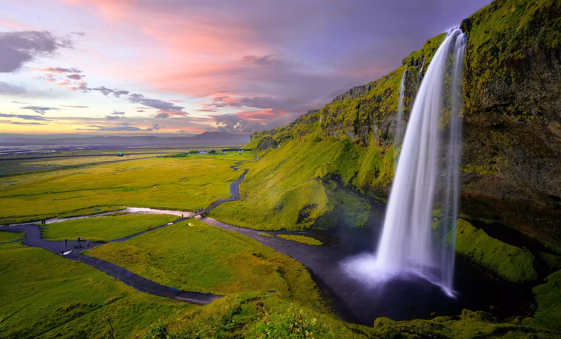 Majestic Seljalandsfoss waterfall cascades at sunset over lush green Iceland South Coast landscape on full-day tour