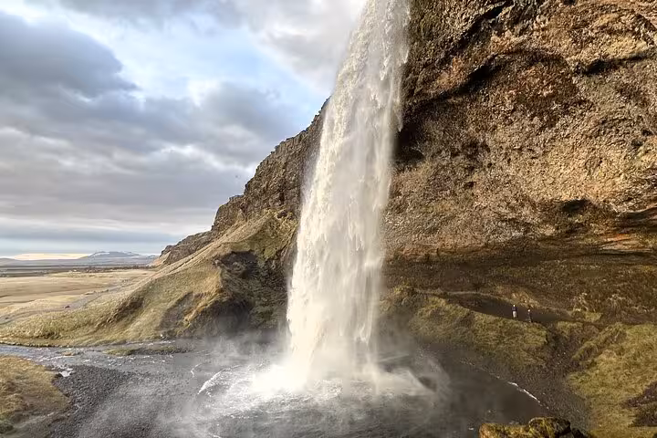 Powerful waterfall cascading down a mossy cliff on Iceland's South Coast with misty spray below