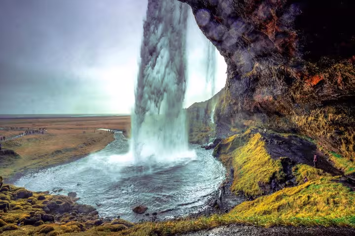 View from behind Seljalandsfoss waterfall on Iceland's South Coast with vast flat plains beyond
