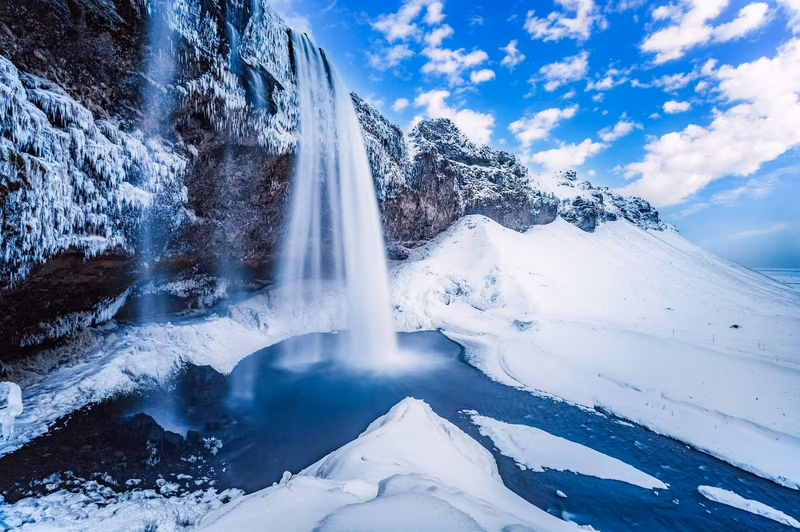 Majestic Seljalandsfoss waterfall surrounded by snow, a must-see on the Iceland stopover tour.