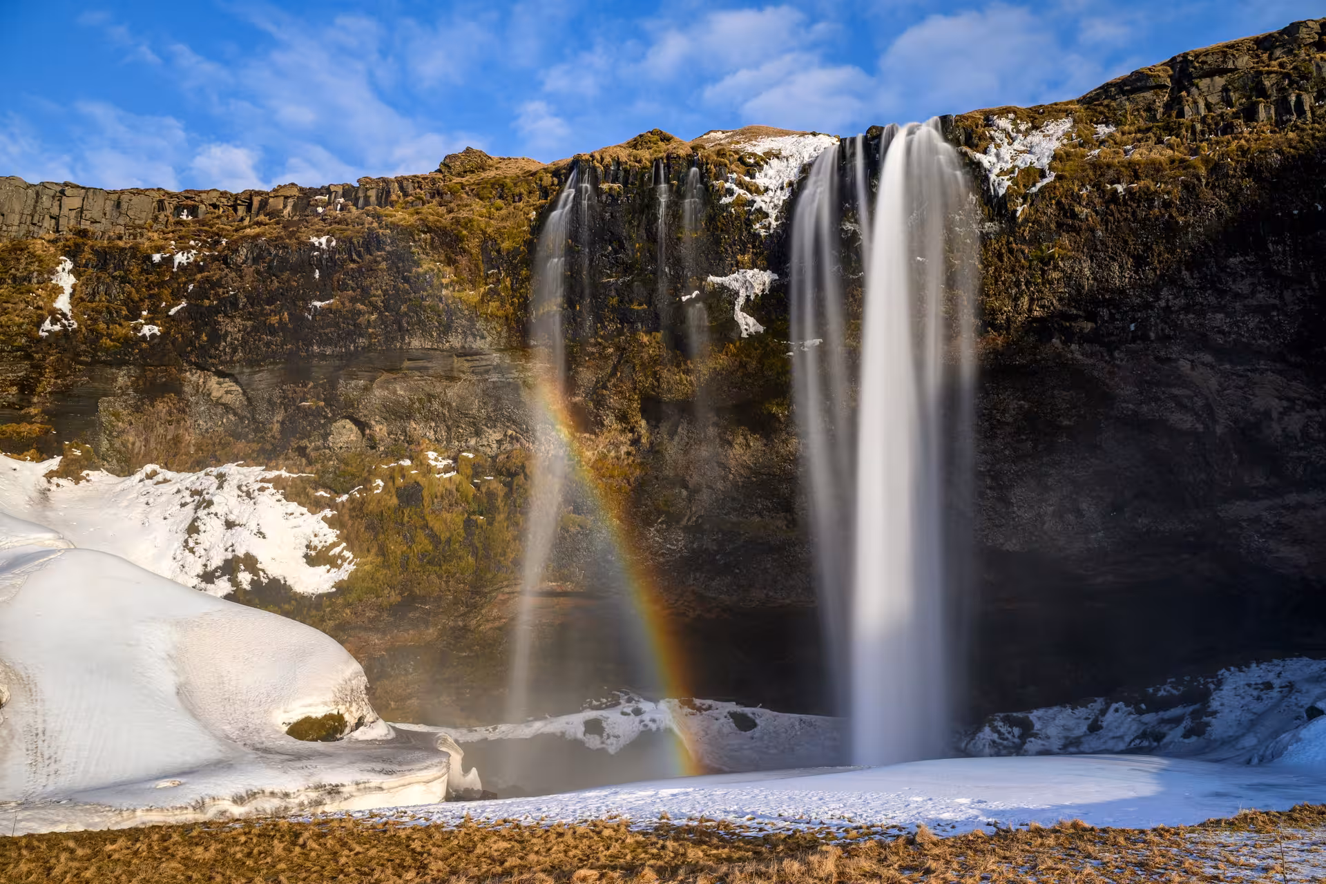 Seljalandsfoss waterfall with rainbow and snow on Iceland's South Coast in winter