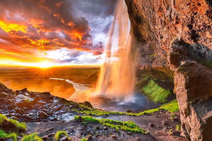 Seljalandsfoss waterfall at sunset on Iceland's South Coast with dramatic orange sky and vast plains